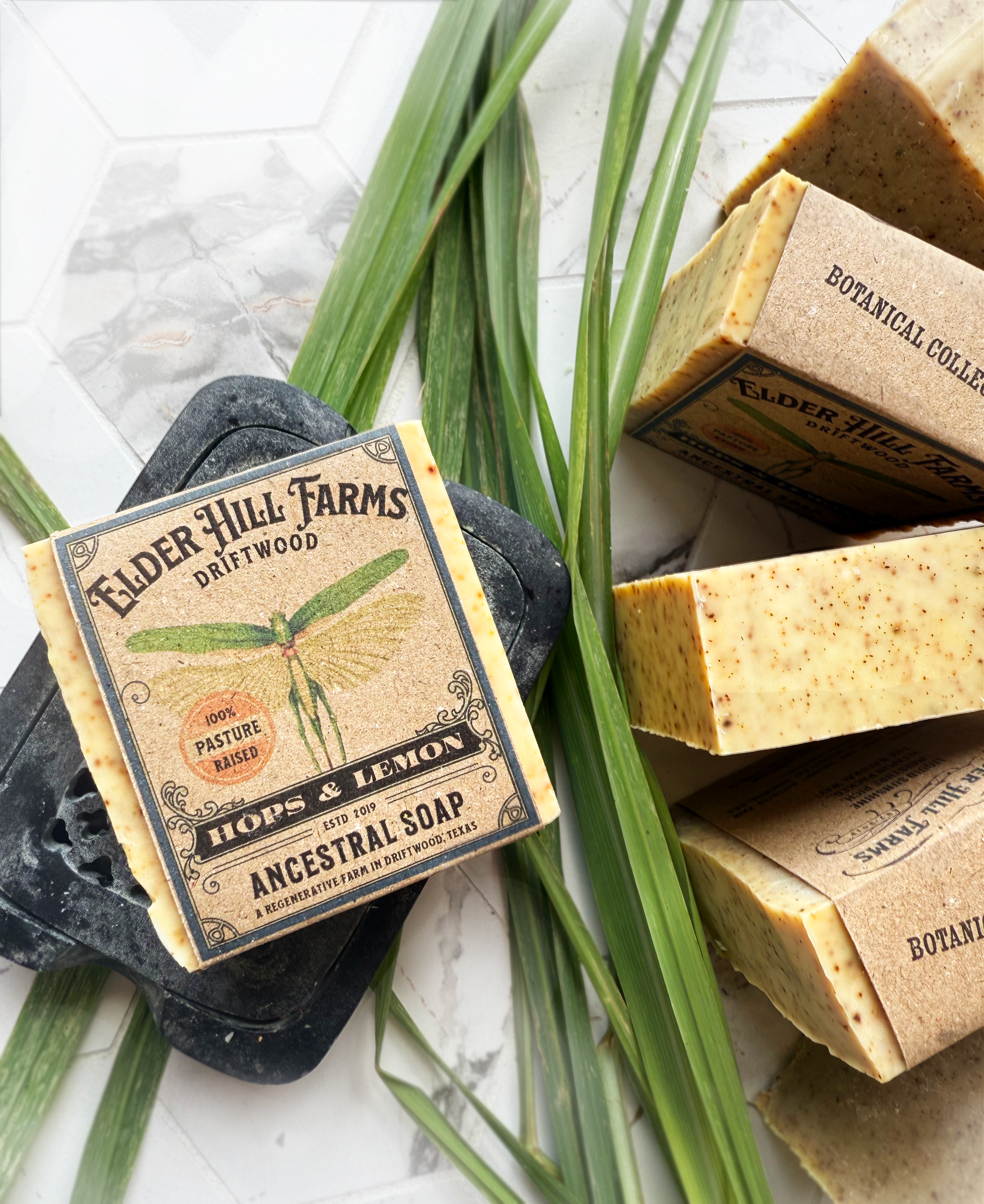Bar of Elder Hill Farms soap with a label on a stone surface with greenery