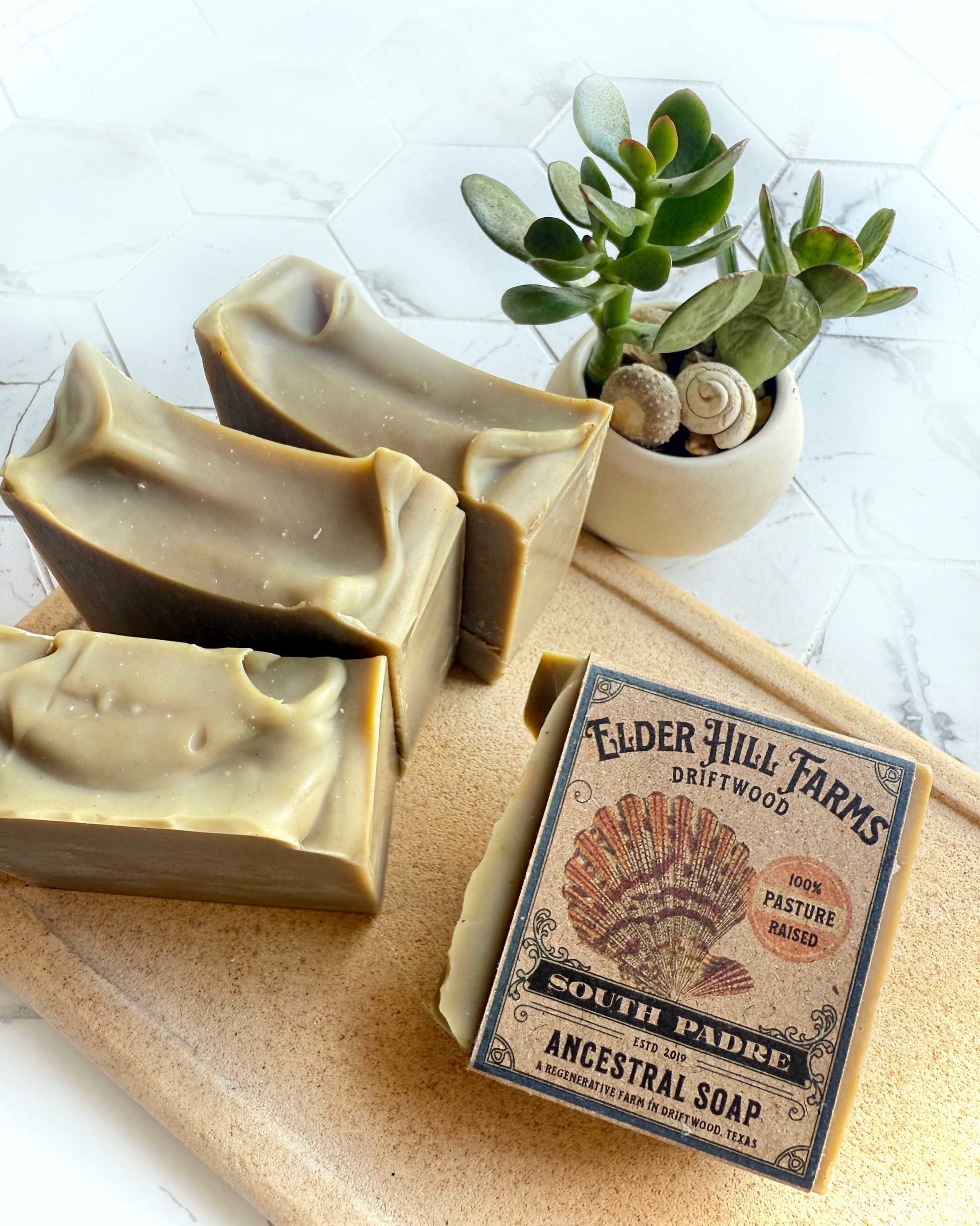 Three bars of Elder Hill Farms soap on a stone board with a plant in the background